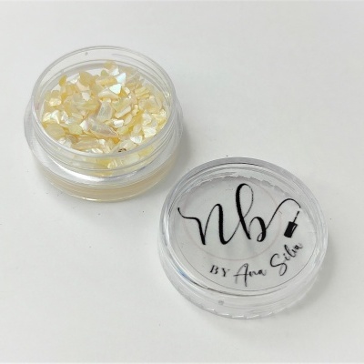 Pote transparente com pigmento perolado amarelo claro e tampa com texto preto 'nb BY Ana Silva'