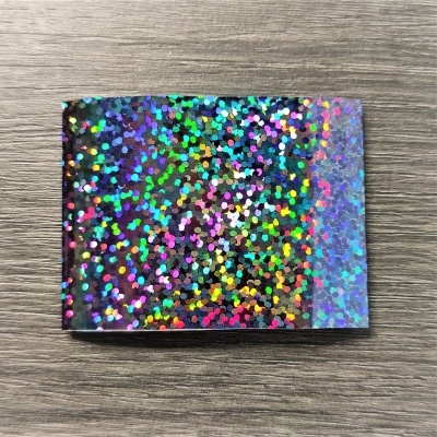 Carteira pequena com padrão holográfico colorido sobre madeira cinzenta