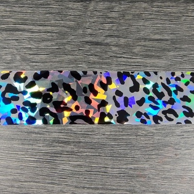 Fita adesiva holográfica com padrão de manchas pretas sobre fundo prateado