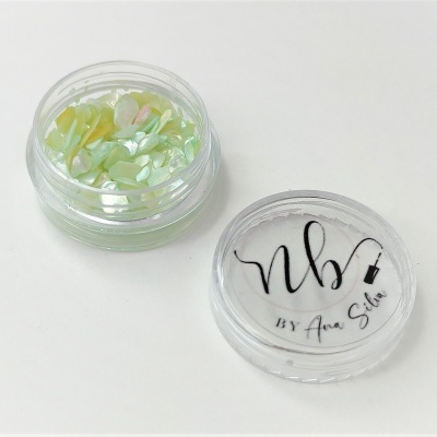 Frasco pequeno transparente com pedaços coloridos e tampa com texto.