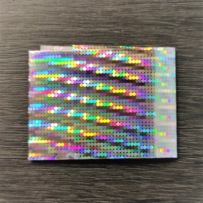 Cartão holográfico com padrão de pontos multicoloridos em fundo de madeira