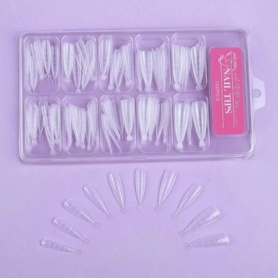 Conjunto de unhas postiças transparentes organizadas em caixa de plástico com etiqueta cor de rosa