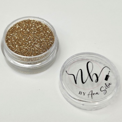 Pó glitter dourado em recipiente com tampa transparente com texto 'nb BY Ana Silva'