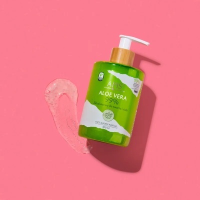 Frasco de gel Aloe Vera 99% verde com doseador, sobre superfície rosa com gel esparramado