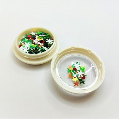 Duas tampas plásticas brancas com confetes coloridos em forma de estrelas e flocos de neve