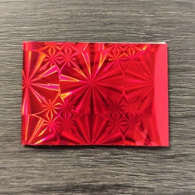 Papel decorativo vermelho metálico com padrão em relevo sobre madeira cinza