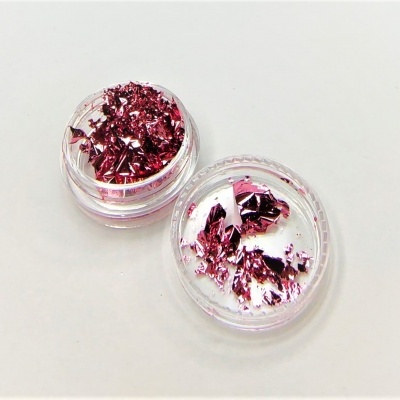 Duas embalagens transparentes com pedaços metálicos cor de rosa.