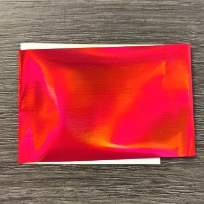 Envelope vermelho refletivo sobre superfície de madeira escura