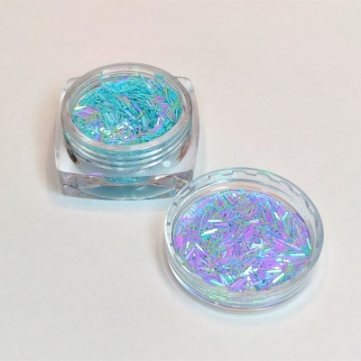 Frasco com glitter holográfico azul e roxo aberto sobre superfície branca