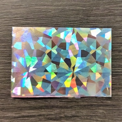 Cartão retangular com padrão holográfico colorido sobre madeira escura