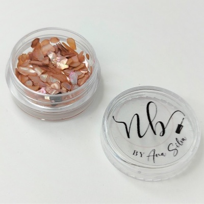 Recipiente transparente com pedaços de conchas castanhas e tampa com texto nb BY Ana Silva