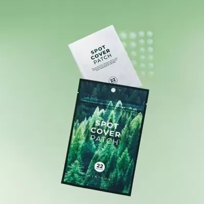 Embalagem verde com floresta e texto SPOT COVER PATCH com saqueta branca e patches transparentes.