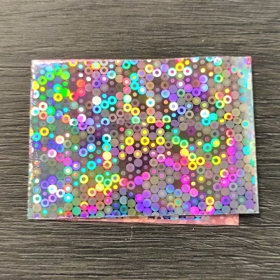 Cartão holográfico com círculos coloridos sobre fundo de madeira cinzenta