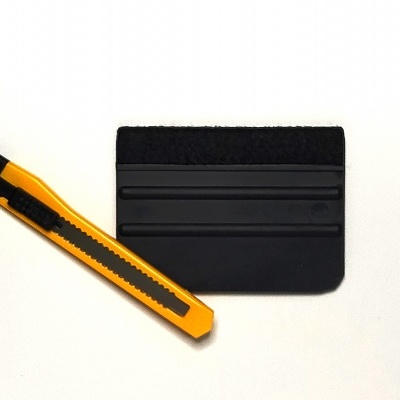 Espátula preta e lâmina de corte amarela sobre fundo branco