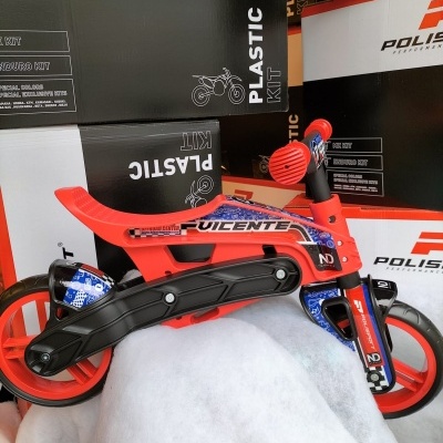 Bicicleta vermelha para crianças com detalhes pretos e azuis em frente a caixas de embalagens