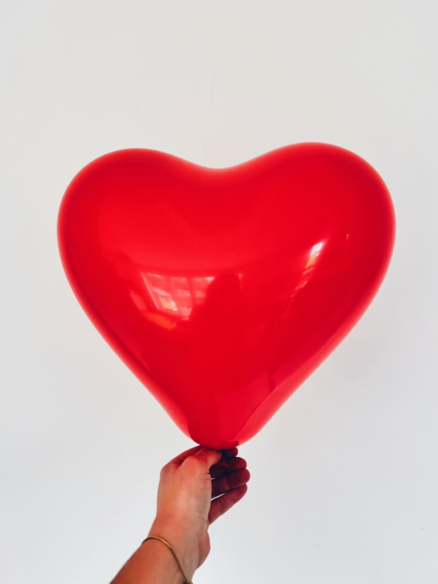 Balão vermelho em forma de coração segurado por uma mão