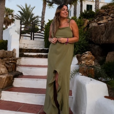 Mulher com vestido verde comprido com abertura frontal em escadaria exterior