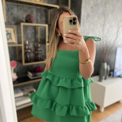 Vestido verde com folhos e alças finas em ambiente interior