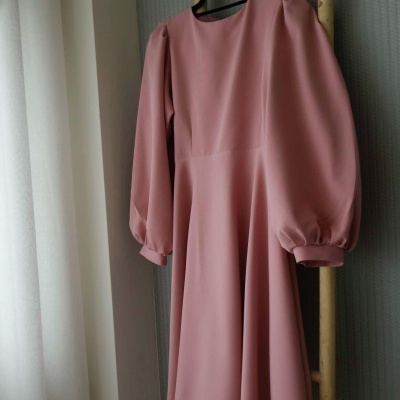 Vestido rosa com mangas bufantes pendurado numa escada de madeira