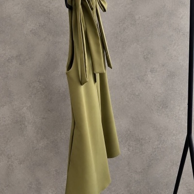 Vestido verde-oliva com alças largas pendurado num cabide preto