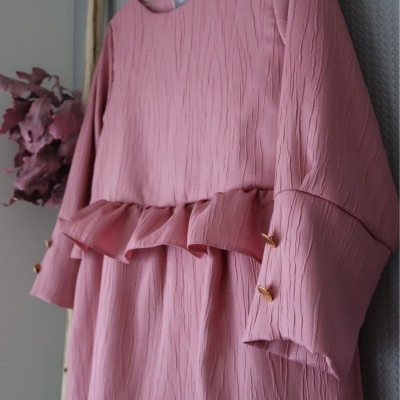 Vestido rosa texturizado com folhos e botões dourados pendurado