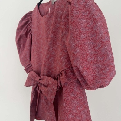 Vestido vermelho com padrão floral e mangas bufantes pendurado num cabide