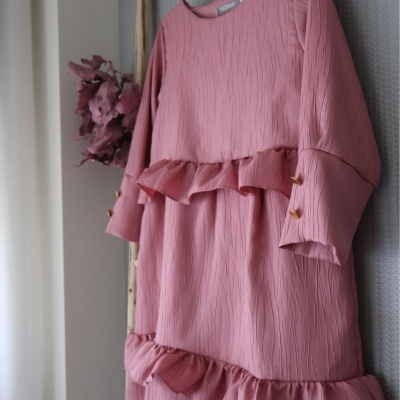 Vestido rosa texturizado com folhos e botões dourados pendurado