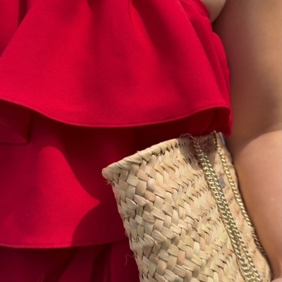 Top vermelho com folhos e colar branco, mala em palha trançada com corrente dourada