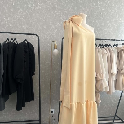 Vestido amarelo claro com um ombro só e laço largo no ombro esquerdo num manequim