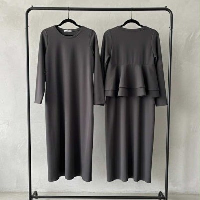 Dois vestidos cinzentos escuros de manga comprida pendurados em cabides preto num cabide de roupa preto