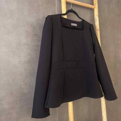 Blazer preto feminino pendurado numa escada de madeira