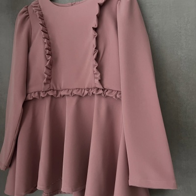 Blusa rosa com folhos e mangas compridas pendurada num cabide