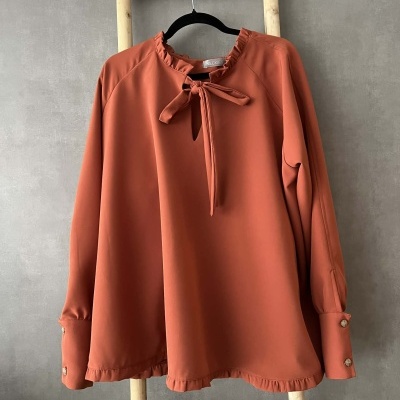Blusa feminina terracota com gola de folho e laço, mangas compridas com punhos e botões.