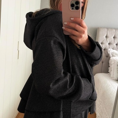 Casaco preto com capuz e bolsos usado por pessoa em quarto