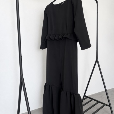 Vestido preto comprido com folhos pendurado em suporte metálico preto