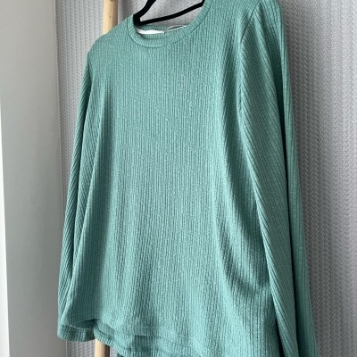 Conjunto de pijama verde água com textura canelada pendurado em cabide.