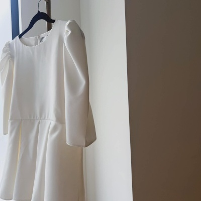 Vestido branco com mangas bufantes pendurado num cabide preto.