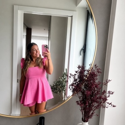 Vestido rosa curto com alças de laço refletido em espelho redondo
