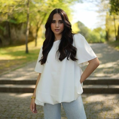 Mulher com blusa branca e calças cinzentas ao ar livre