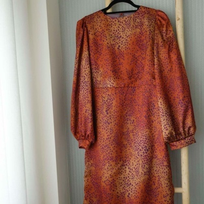 Vestido laranja com padrão de pintas pendurado em escada de madeira