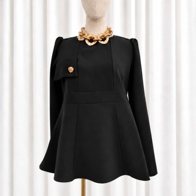 Blusa preta com botão dourado e colar de elos em manequim