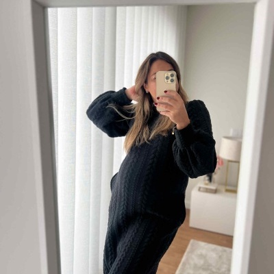 Mulher a tirar selfie em espelho com vestido preto de malha trançada e mangas compridas