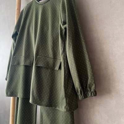 Conjunto de pijama verde-oliva com pontos brancos pendurado num cabide