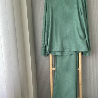 Conjunto de camisola e saia verde claro canelados pendurados em estrutura de madeira