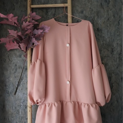 vestido rosa claro com mangas bufantes pendurado numa estrutura de madeira