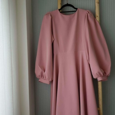 Vestido rosa de manga comprida pendurado numa escada de madeira