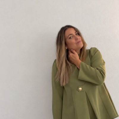 Mulher com blazer verde-oliva e calças creme em fundo branco
