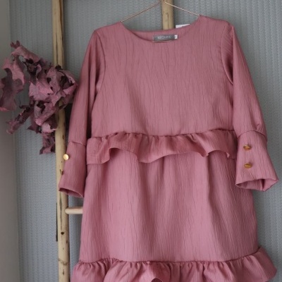 Vestido rosa com folhos pendurado numa escada de madeira