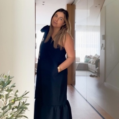 Mulher vestindo vestido longo preto sem mangas dentro de casa com chão de madeira