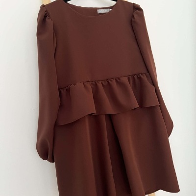 Vestido castanho com folho à cintura pendurado num cabide